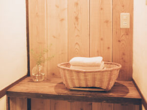 ネドコロノラの脱衣スペース。福江島の古民家の木棚にタオルと小花の一輪挿し